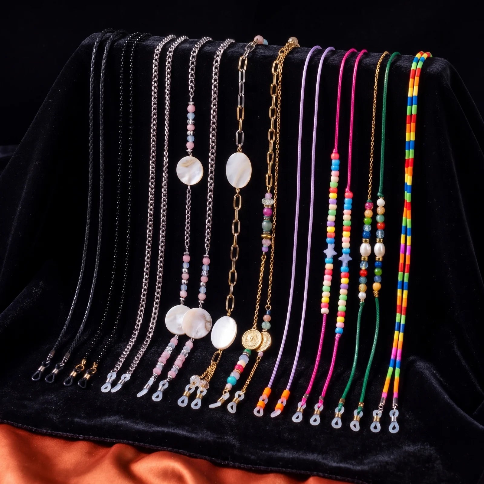 Our eyewear chains hanging on black velvet over orange satin